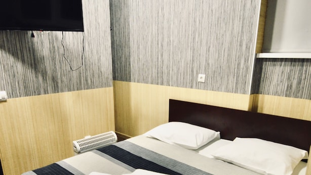 Une chambre d’hôtel avec un lit, un téléviseur à écran plat fixé au mur et un plancher en bois.