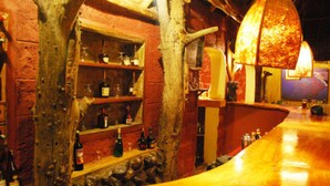 A rustic bar area with wooden shelves and a polished wooden counter. - Flamingo Hill Tented Camp (Nakuru)