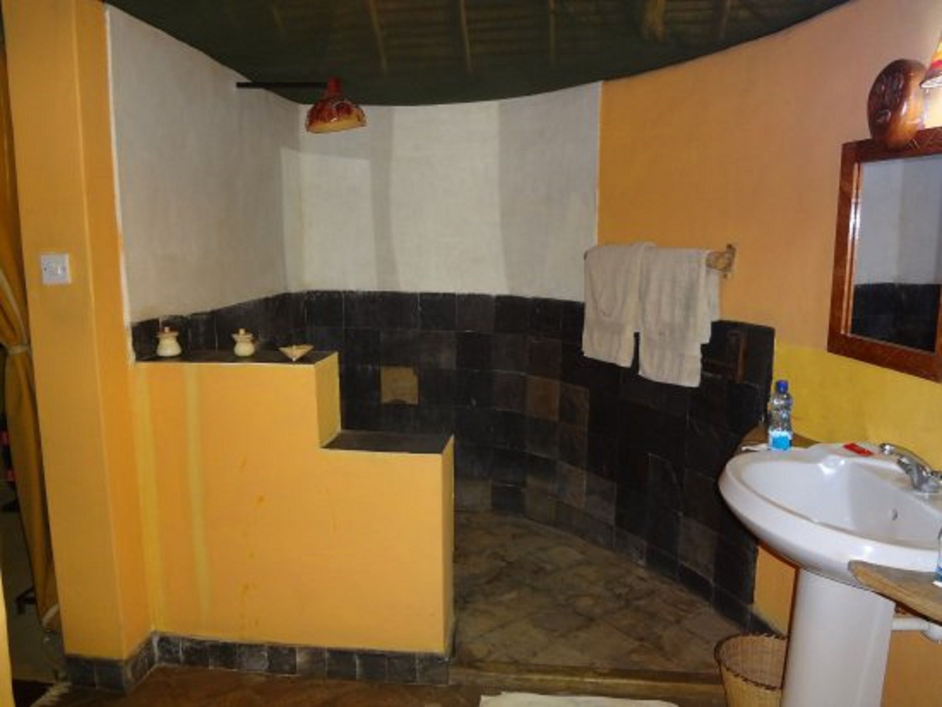 Casa de banho com lavatório, espelho, porta-toalhas e zona de duche com chão em mosaico.