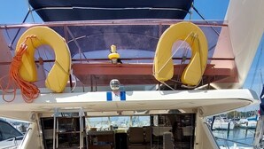 Een scheepdek met een overdekte zithoek, een tafeltje en een reddingsboei.