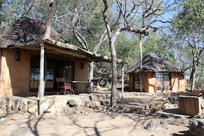 A rustic building with a thatched roof, stone steps, and a wooden chair outside.