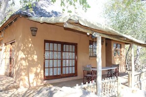 A building with a large window, a covered porch, and a white fence.