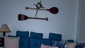 Un dormitorio con cama, cubierta con colcha azul y blanca a rayas, varios cojines, incluyendo uno con diseño de flamenco, y un adorno en la pared.