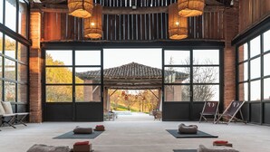 A spacious room with large windows, yoga mats, and chairs arranged for relaxation. - L'Ostalas (Lafrancaise)
