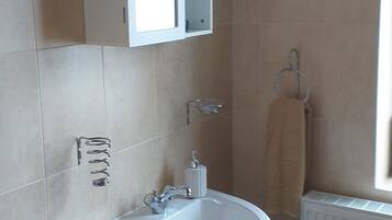 A bathroom with a white sink, a cabinet, and a towel hanging on a hook.