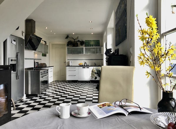 A modern kitchen with a checkered floor, stainless steel appliances, and a dining area with a table set for tea.