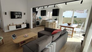 A modern living room with a grey sofa, a wooden coffee table, and a TV mounted on the wall. - Villa with private pool in Cap d'Artrutx. (Cala en Bosc)