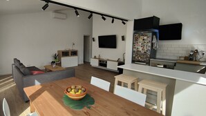 A modern kitchen with a dining area, a grey sofa, and a TV mounted on the wall. - Villa with private pool in Cap d'Artrutx. (Cala en Bosc)