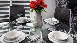A dining table set with white plates, silverware, and a clear glass vase with red flowers. - 2 Bedrooms Sleeps 6 Near Top Blackpool Attractions (Blackpool)