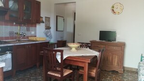 A compact kitchen with wooden cabinets, a dining table with chairs, and a television on a wooden cabinet. - two-room apartment with veranda (NOTO)