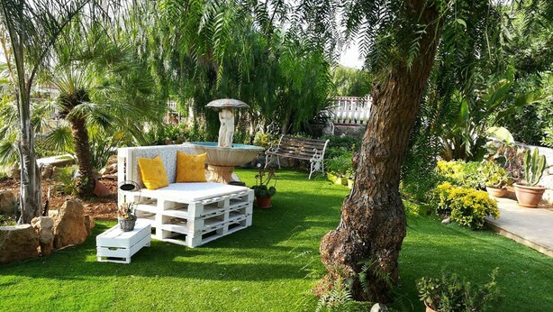 An outdoor seating area with a white sofa, yellow cushions, and a stone fountain. - two-room apartment with veranda (NOTO)