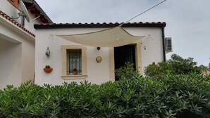 A building with a tiled roof, a window with a metal grill, a door, and a wall-mounted air conditioning unit. - two-room apartment with veranda (NOTO)