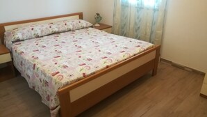 A bed with a floral bedspread, wooden headboard, and a nightstand with a lamp. - two-room apartment with veranda (NOTO)