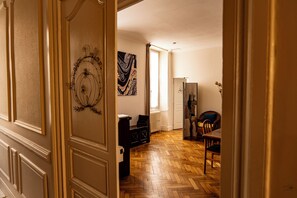 A hallway with a wooden herringbone floor, a black bench, and a dining area with a table and chairs. - La Maison Duffour (Tonneins)
