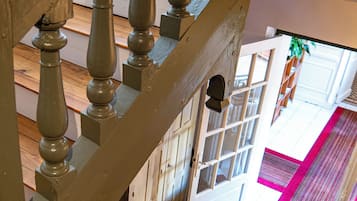 Un escalier en bois, recouvert d’une moquette à motifs, offre une vue sur une pièce dotée d’une porte et d’une fenêtre.