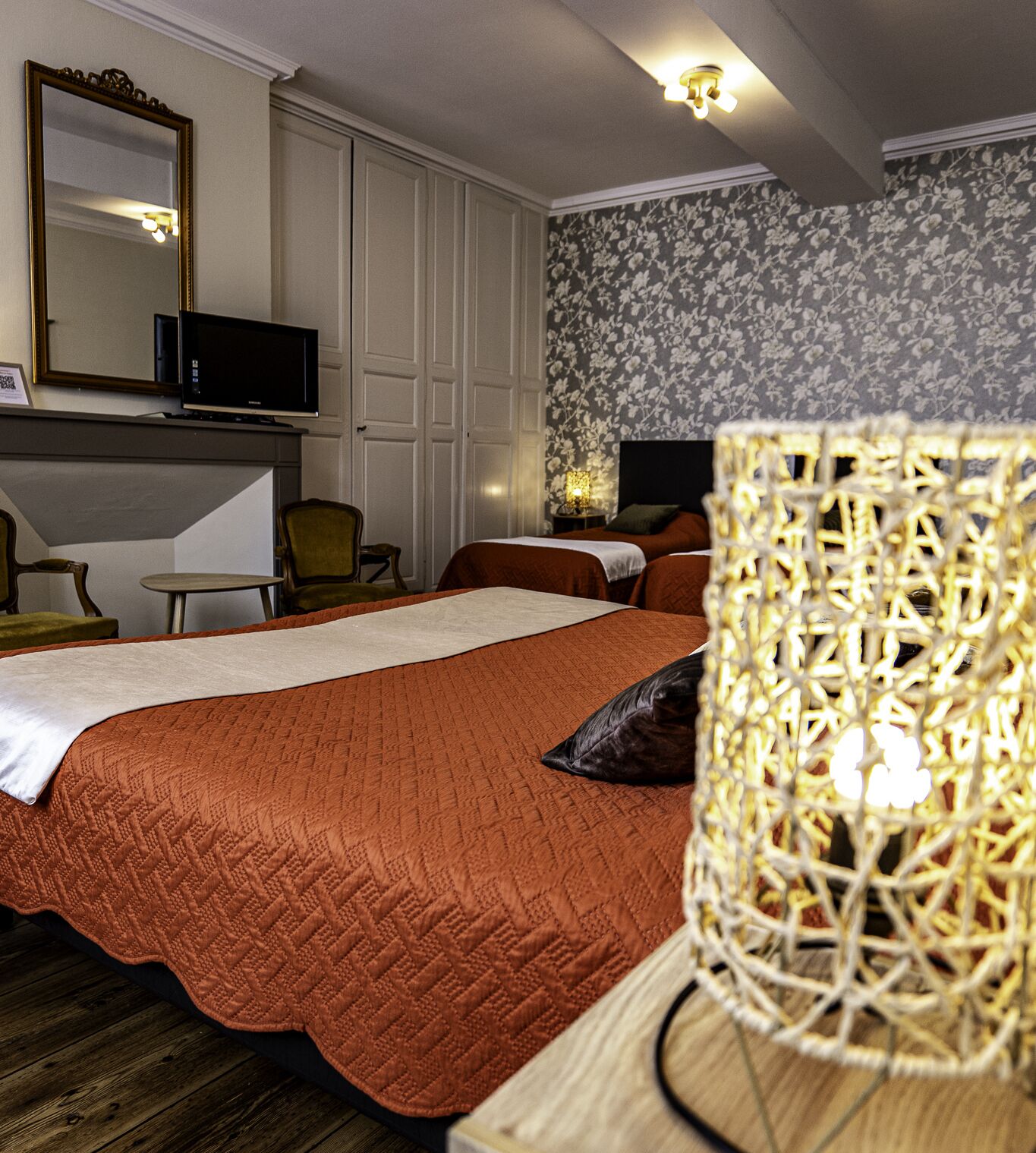 Et hotelværelse med seng, fjernsyn, stol og dekorativ lampe.