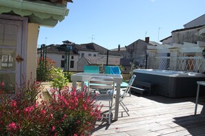A wooden deck with a hot tub, a table, and chairs. - La Maison Duffour (Tonneins)