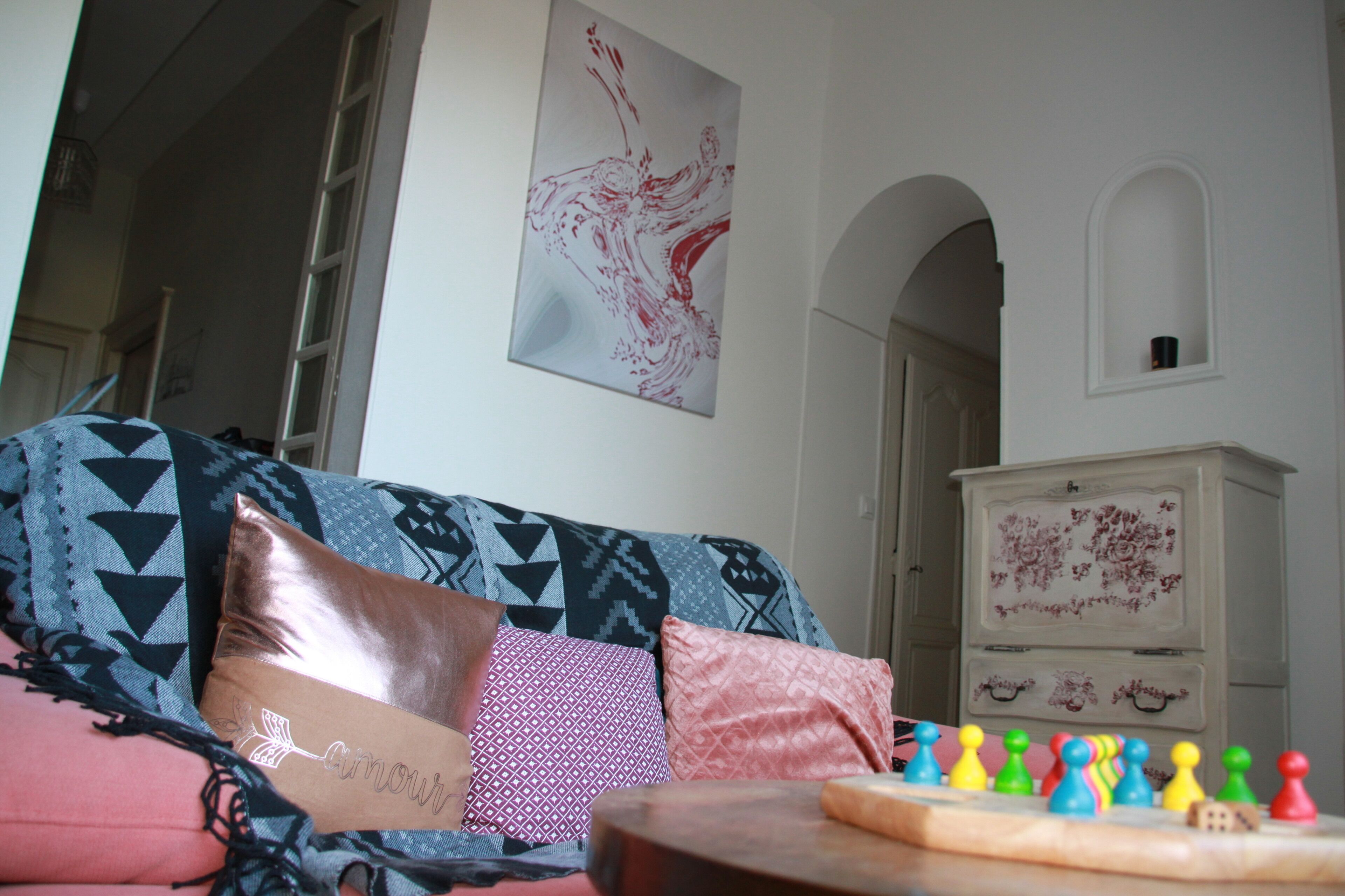 Una sala de estar con un sofá estampado, un mueble de madera y un tablero de ajedrez.
