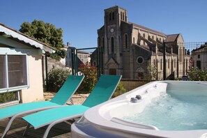 A hot tub with lounge chairs, a church with a bell tower, and a clear blue sky. - La Maison Duffour (Tonneins)