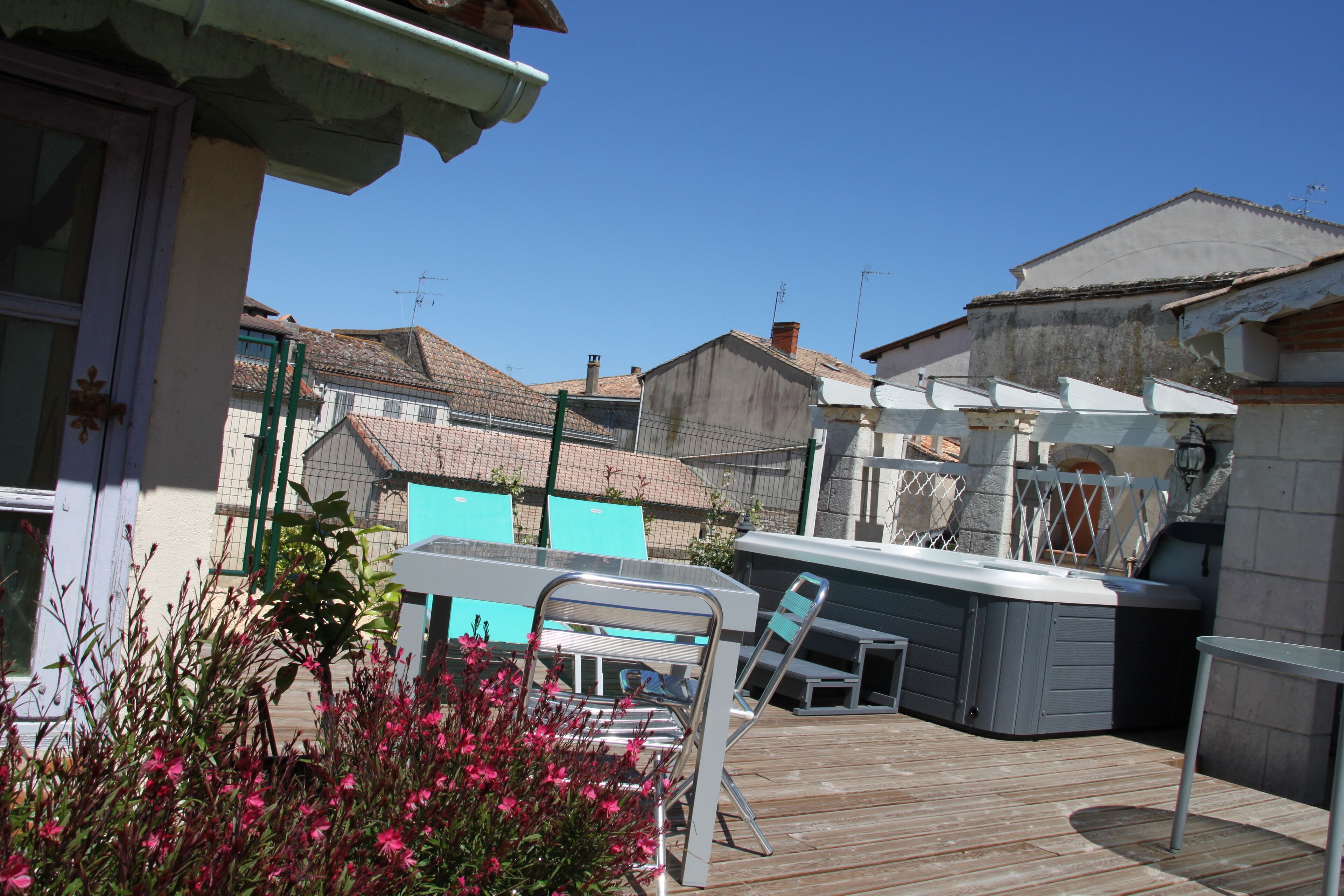 A patio area with a wooden deck, a hot tub, and a seating area with chairs and a table.