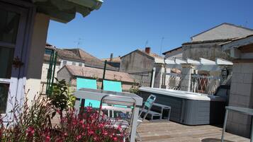 A patio area with a wooden deck, a hot tub, and a seating area with chairs and a table.