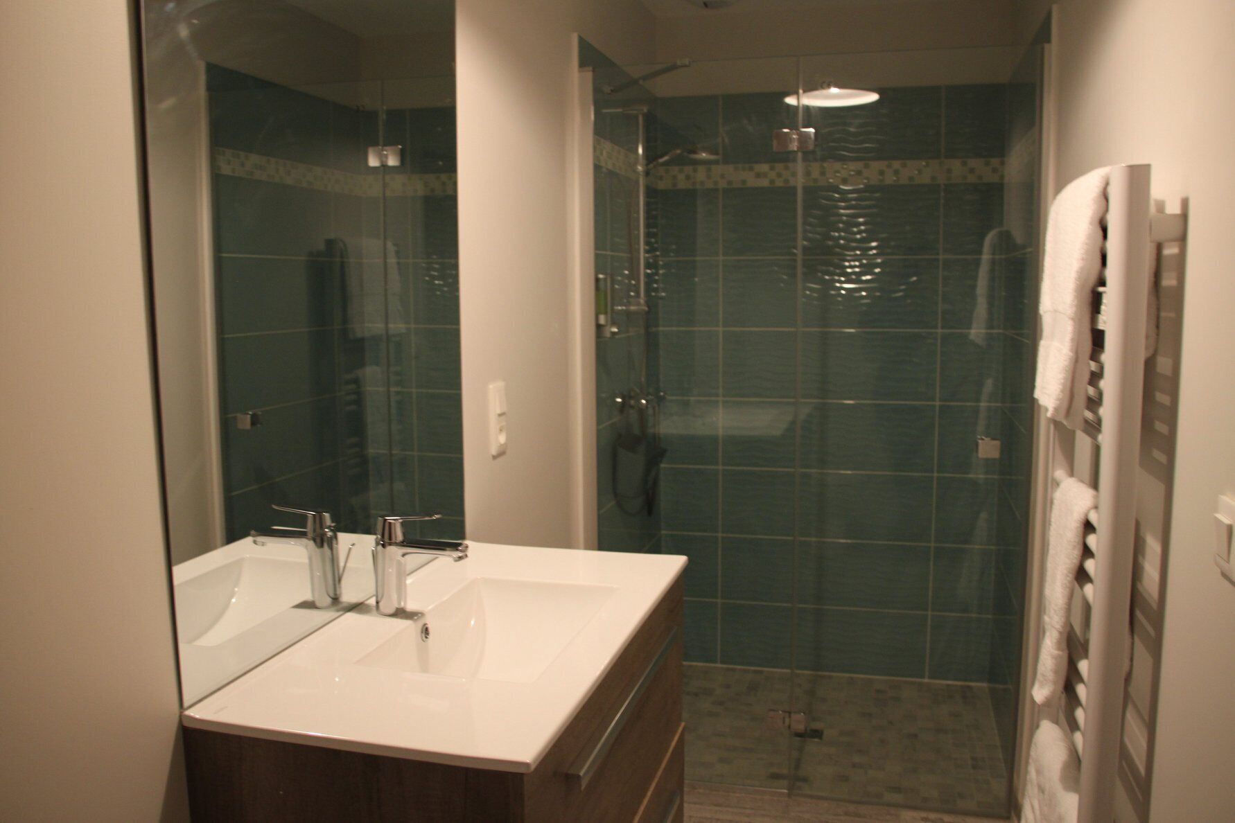 A bathroom with a white sink, mirror, and glass shower enclosure.