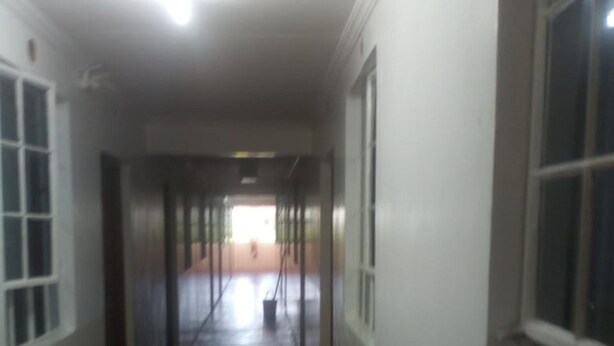A long, narrow hallway with a red carpet, white walls, and large windows on one side. - Freetown Bar And Restaurant (Nairobi)