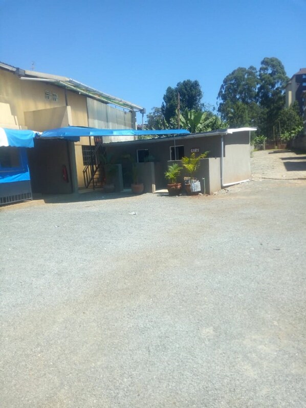 A small building with a blue awning, a sign that reads "GENTS", and a few potted plants. - Freetown Bar And Restaurant (Nairobi)
