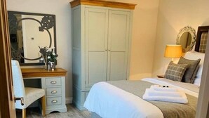 A bedroom with a bed, a desk, a wardrobe, and a mirror. - Homely luxury cottage 2 (Tantobie)