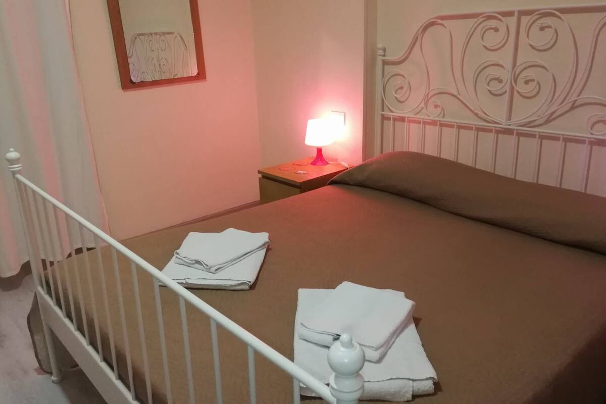 A neatly made bed with white linens, a bedside lamp, and a decorative headboard.
