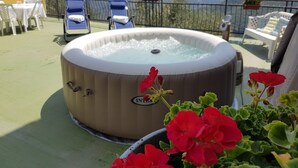 A hot tub on a terrace with a mountain view, surrounded by lounge chairs and potted plants. - DINOABBO FARMHOUSE APP. OLIVE TREES CITR:008033-AGR-0001 CIN IT008033B5JCTY5SHI (Lucinasco)