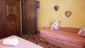 A bedroom with a wooden wardrobe, a bed with pink bedding, and two heart-shaped wall decorations. - DINOABBO FARMHOUSE APP. OLIVE TREES CITR:008033-AGR-0001 CIN IT008033B5JCTY5SHI (Lucinasco)