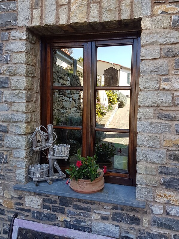 A stone building with a window featuring a wooden frame and a welcome sign.
