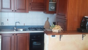 A kitchen with wooden cabinets, a sink, a stove, and a coffee maker. - DINOABBO FARMHOUSE APP. OLIVE TREES CITR:008033-AGR-0001 CIN IT008033B5JCTY5SHI (Lucinasco)