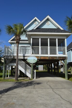 A two-story house with a balcony, a wooden deck, and a sign indicating it is a rental property.