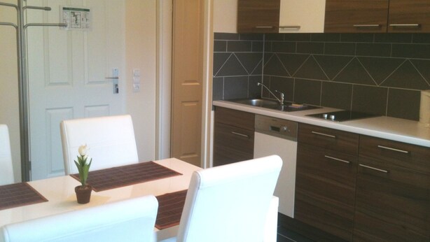 Una cocina moderna con armarios de madera oscura, encimera blanca y lavavajillas integrado.