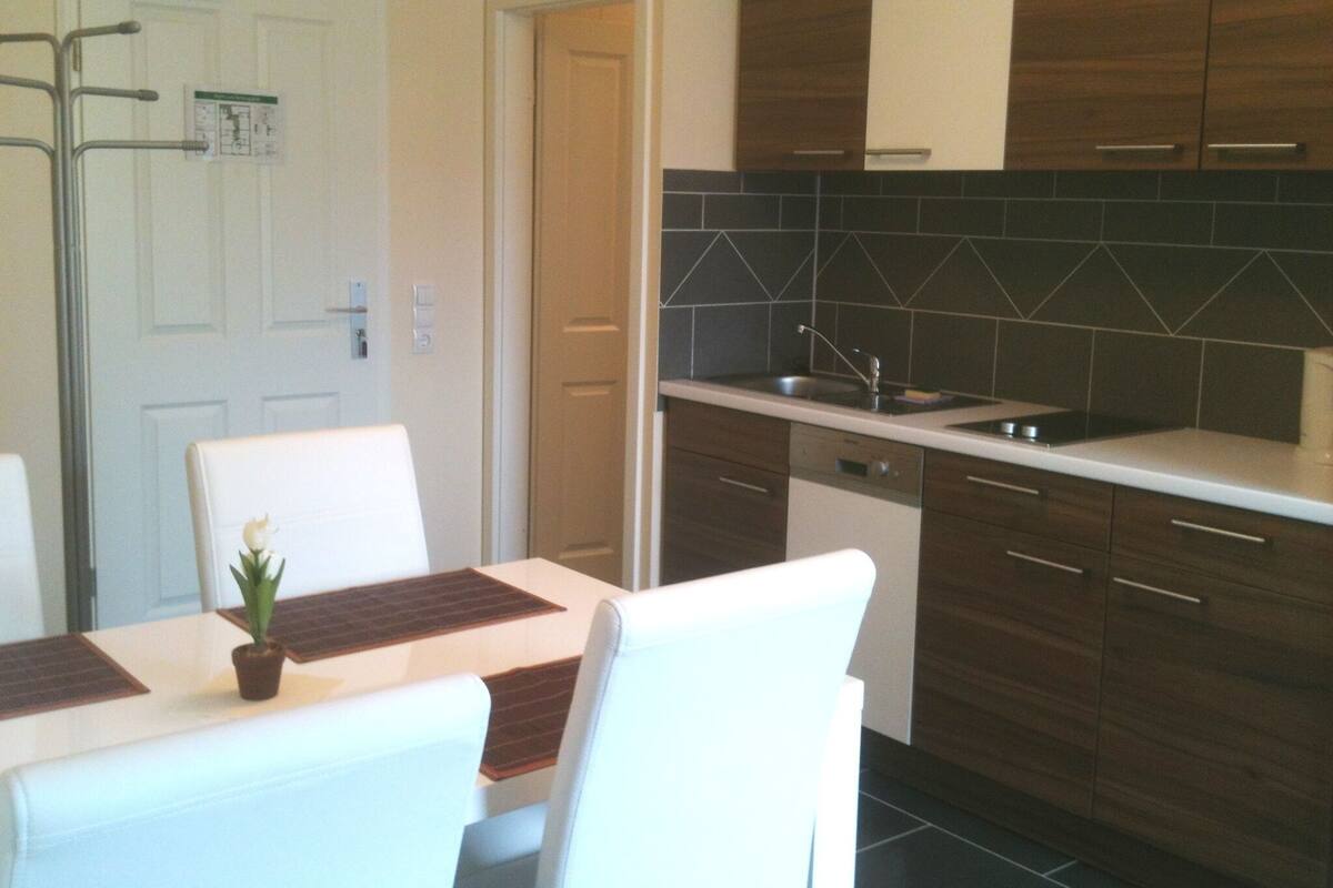 A modern kitchen with dark wooden cabinets, a white countertop, and a built-in dishwasher.