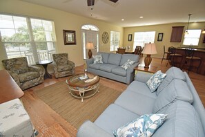 A living room with a sofa, armchairs, a coffee table, and a dining area with chairs and a table.