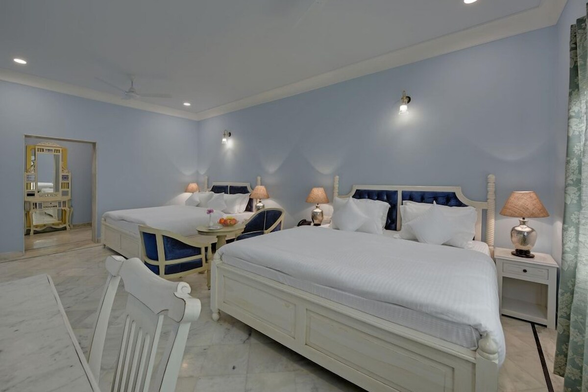 Quarto de hotel com duas camas, um espaço de estar e um espelho.