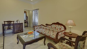 Una sala de estar con un sofá, una mesa de centro, una lámpara y un sillón.