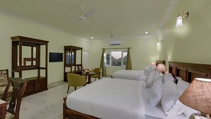 Habitación de hotel con una cama grande, dos mesitas de noche, un escritorio con silla, un armario de madera, un televisor y una ventana con cortinas.