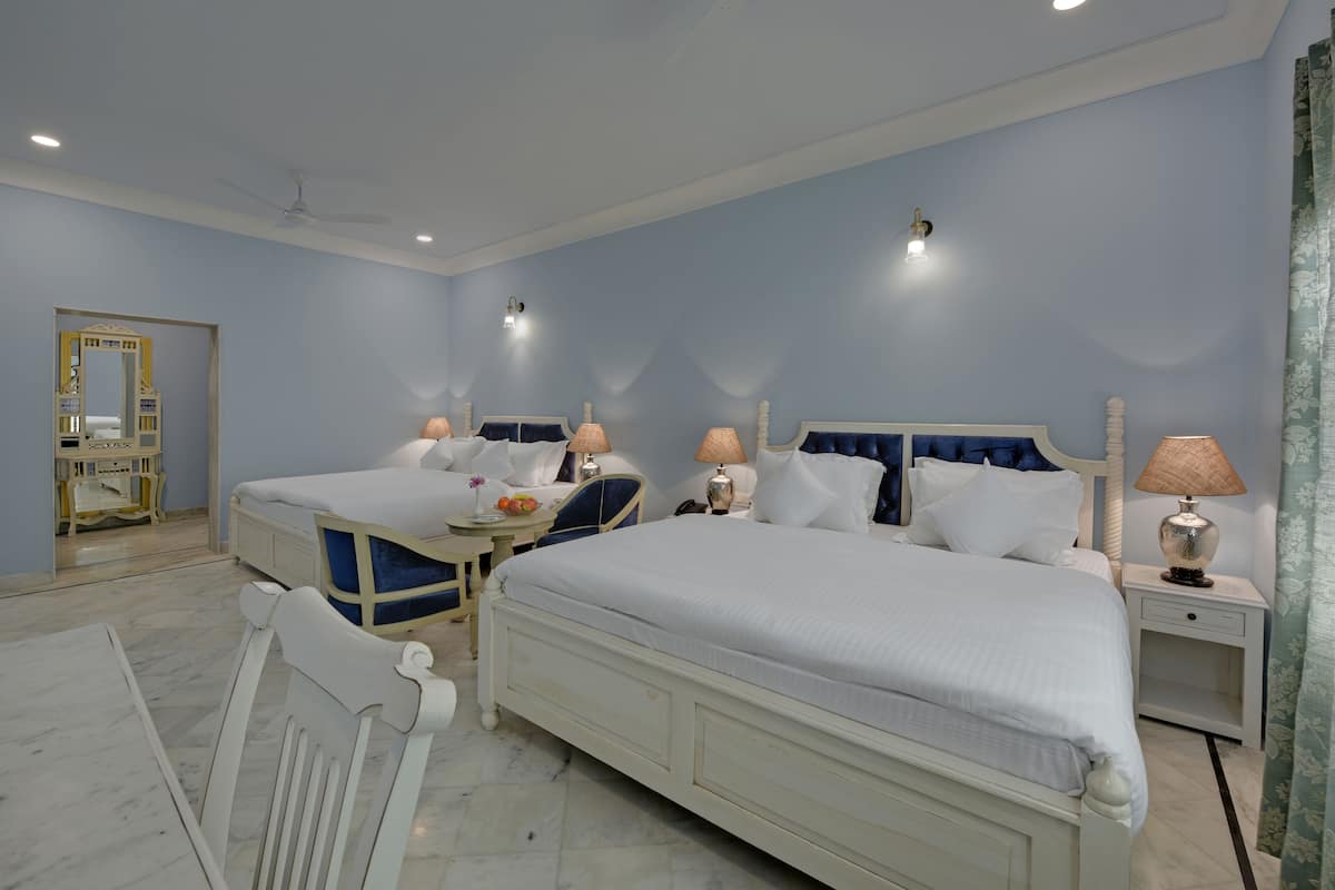 A hotel room with two beds, a vanity, a mirror, and a ceiling fan.