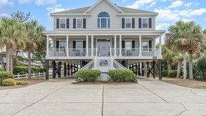 A two-story house with a balcony, a front porch, and a small staircase leading to the entrance. - All Aboard - Oceanfront in Garden City Beach (Garden City)
