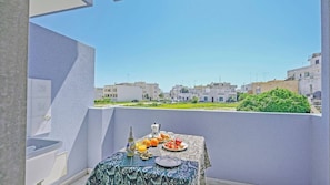 A balcony with a table set for breakfast, a view of residential buildings, and a clear sky.