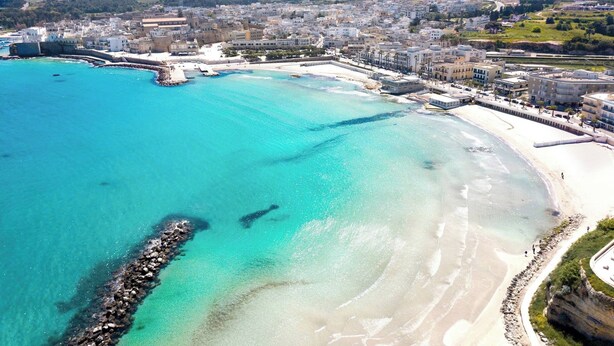 An aerial view of a coastal city with a clear blue sea, sandy beaches, and a mix of residential and commercial buildings. - Near The Beach And The Center Of Otranto - Apartment Eleonora 5 Places (Otranto)