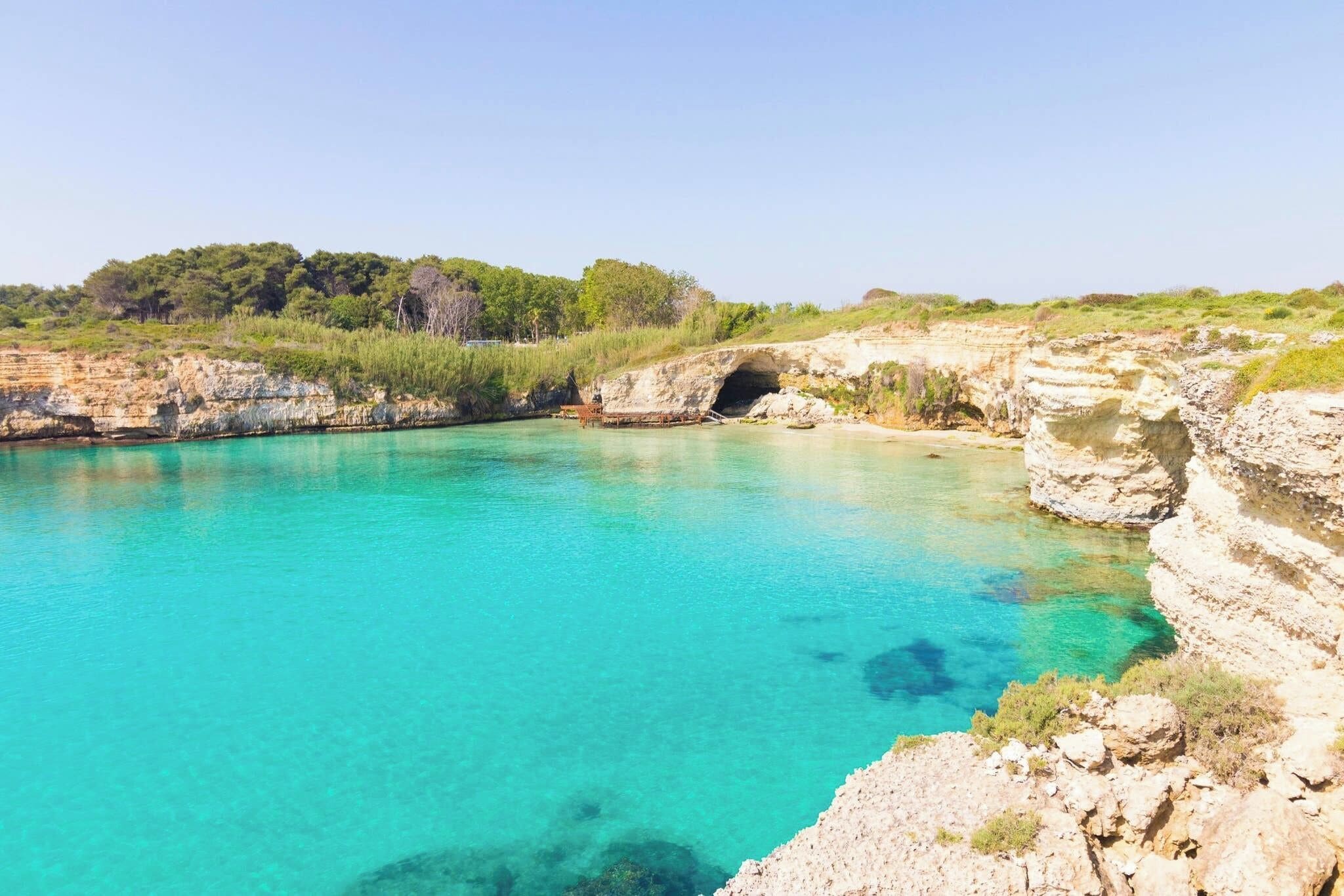 A natural pool surrounded by rocky cliffs and greenery.