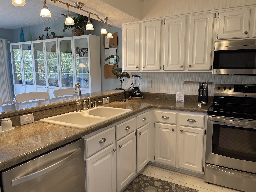 A modern kitchen with white cabinetry, stainless steel appliances, and a granite countertop.