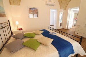 Une chambre à coucher avec un lit, des oreillers, une table de chevet, une lampe et un tableau au mur.
