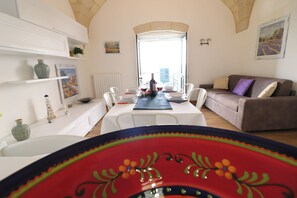Un coin repas avec une table dressée pour deux personnes, un canapé et une vue sur la ville.