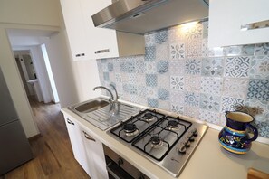 Une cuisine équipée d’une cuisinière à gaz, d’un évier en acier inoxydable et d’un crédence décorée.
